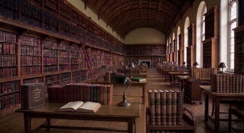 A grand library hall with shelves along the walls, arched windows and reading tables; in front, a wooden table laden with old leather-bound books.